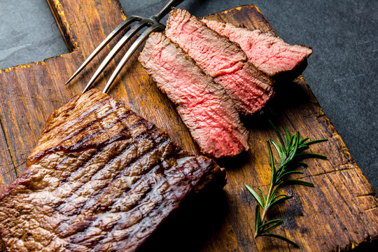 Sliced grilled medium rare beef tenderloin steak served on wooden board.. Top view