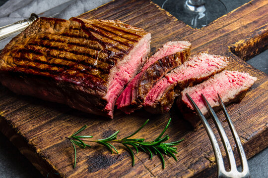 Sliced grilled medium rare beef tenderloin steak served on wooden board.. Top view
