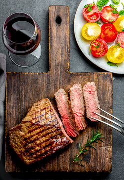 Sliced grilled medium rare beef tenderloin steak served on wooden board.. Top view
