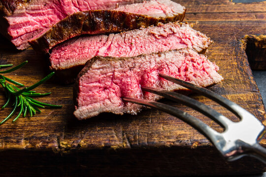 Sliced grilled medium rare beef steak served on wooden board Barbecue, bbq meat beef tenderloin. Top view, slate background