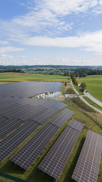 Aerial view of the VISPIRON Solarpark with rows of photovoltaic panels, charging infrastructure, and surrounding green fields in Egling, Bavaria, Germany.