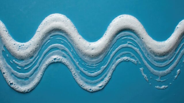 White soap suds formed into a wavy line on a bright blue background