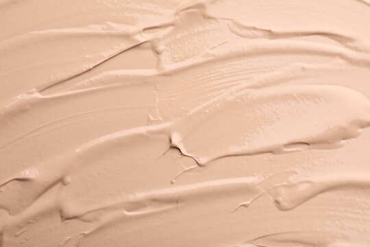 Swatches of liquid foundation as background, top view