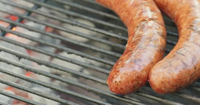 Juicy sausages sizzle over hot charcoal as juices render on grate