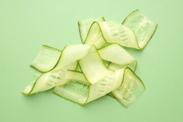 Obraz premium Slices of ripe cucumber on green background, flat lay