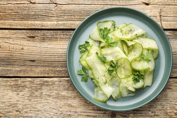 Obraz premium Tasty salad with cucumber slices and herbs served on wooden table, top view. Space for text