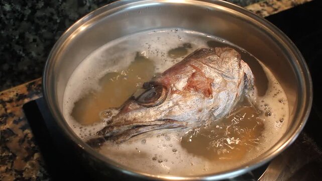 Cooking fish head with vegetables in boiling water for stock