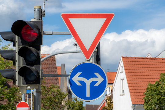 Traffic signs at an intersection with a red light and a yield sign during the day