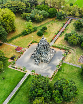 Aerial view of Bubrah Temple surrounded by lush green lawns, stone pathways, and trees in the archaeological park in Kecamatan Prambanan, Jawa Tengah, Indonesia.