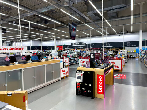 Spacious modern electronics retail store interior featuring gaming laptops and branded technology displays with bright LED lighting and organized product sections