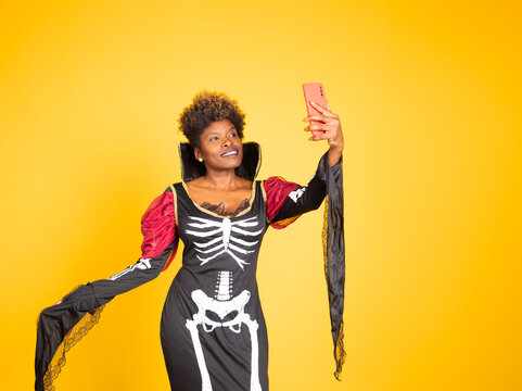 Black woman wearing halloween skeleton costume taking selfie