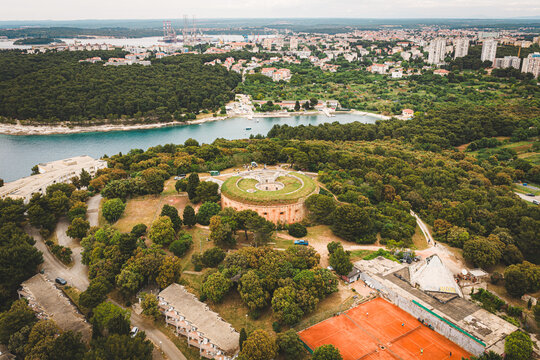 Aerial view of Fort Bourguignon surrounded by lush pine forests and nearby tennis courts with the city of Pula in the background, Pula, Istria County, Croatia.