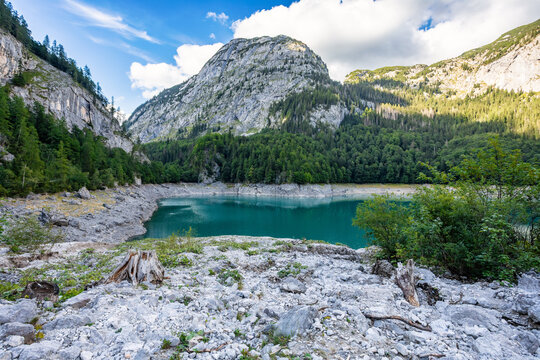 Turquoise Gosausee lake reflecting lush green forest and rugged mountains