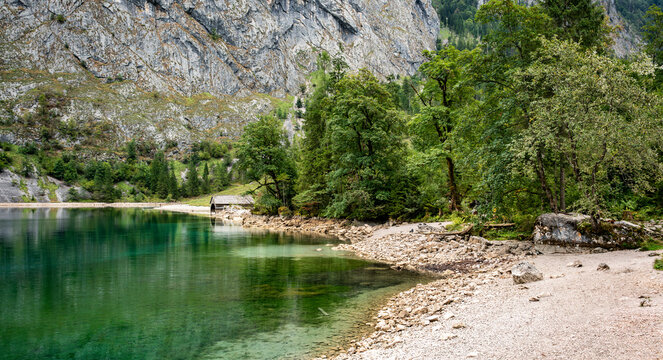 Serene Alpine Lake With Lush Greenery And Rocky Shoreline In Bavaria Germany