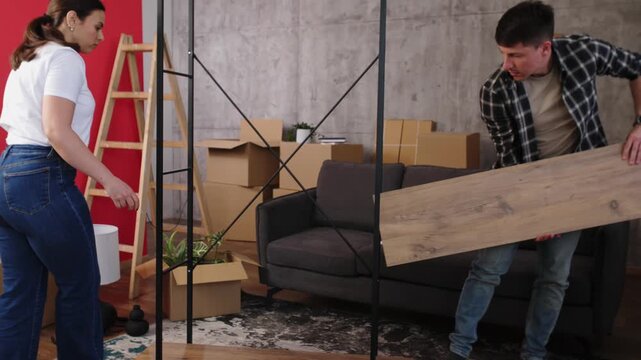 Young couple assembling new furniture together in apartment