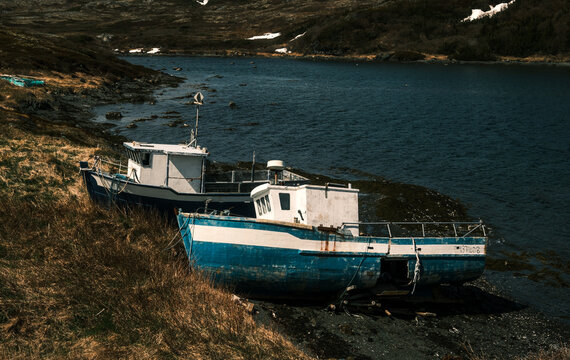 Small white and blue wooden fishing boat anchored in calm ocean bay in Newfoundland Canada