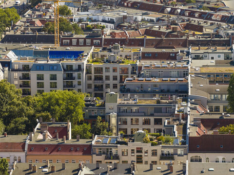 Aerial view of the Friedrichshain district in Berlin featuring dense residential buildings with varied rooftops, green trees, and a construction crane in Berlin, Berlin, Germany.