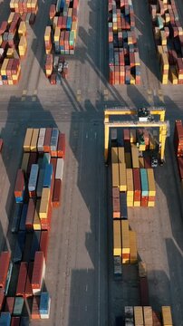Top down aerial view shipping container terminal in Port of Valencia Spain organized cargo stacks and gantry crane summer logistics industry vertical slow motion video stock
