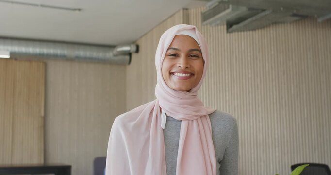 Adult African American woman in hijab reacting, smiling in office, frame tightening, showing watch