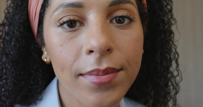 African American woman blinking, leaning, smiling in soft room, collared shirt, headband