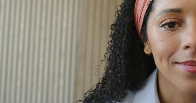 Adult African American woman wearing headband blinking and smiling moving at ridged wall