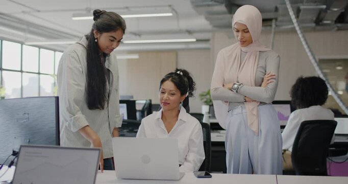 Diverse women reviewing laptop onsite left woman pointing center typing right viewing smartphone