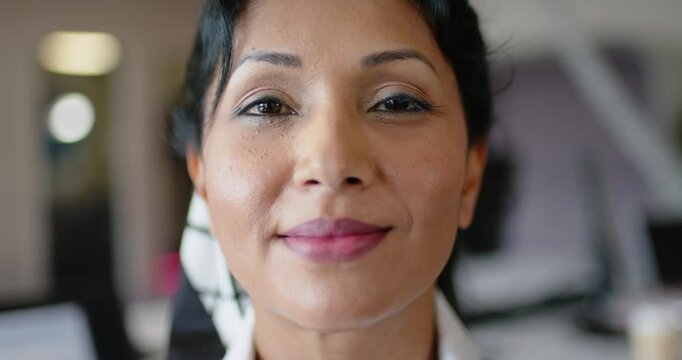 Woman holding eye contact, smiling then laughing in salon, wearing white shirt and headscarf