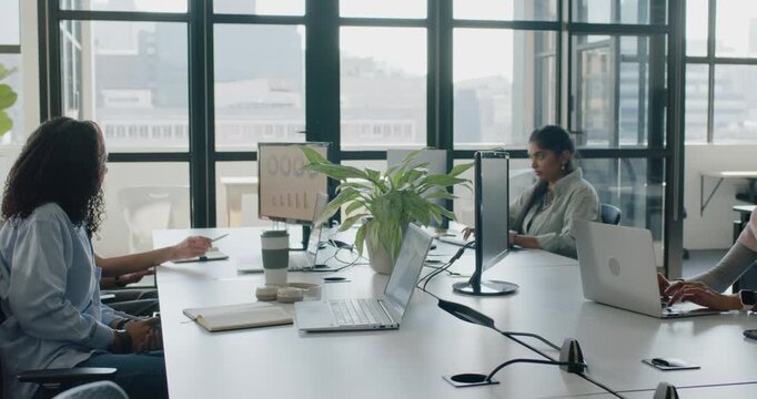 Diverse female staff at table, pointing driving work, center using phone right typing PC