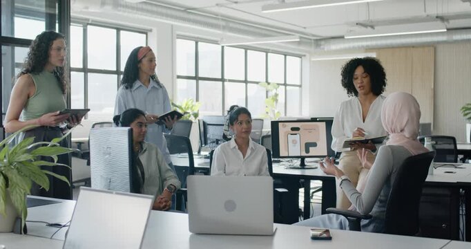 Diverse female coworkers in workwear meeting around laptop and monitor mockup, driving discussion
