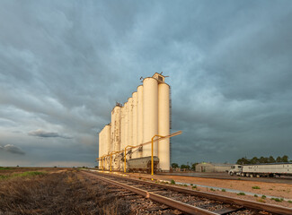 Train tracks next to grain silos during a stormy sunset © cherylvb