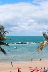 Paisagem de praia tropical vista entre folhas de coqueiro, com mar calmo, pequenos barcos ao longe e céu nublado, na Praia do Francês, Alagoas, Brasil, litoral do Nordeste brasileiro © nathana