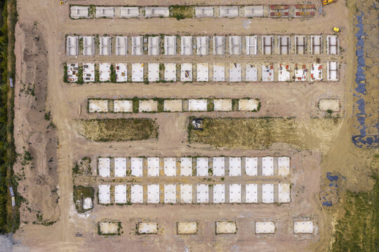 Aerial view of a BESS construction site with rows of concrete foundations and modular structures arranged in a grid pattern on a dirt field.