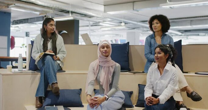 Diverse team in office, curly using mic starting talk, hijab listening, later joining, taking notes