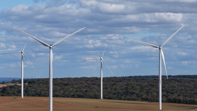 vue a&eacute;rienne en gros plan des &eacute;oliennes et du parc &eacute;olien d'Ottange en Moselle. Les pales et les nacelles blanches tournent sur un ciel bleu l&eacute;germent nuageux. Frrance septembre 2026 