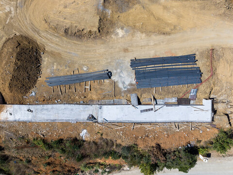Aerial view of a construction site with concrete foundations, stacks of steel rebar, and excavated earth in Istanbul, Istanbul, Turkiye.