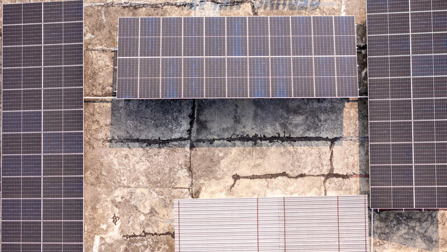 Aerial view of solar panels installed on a weathered concrete roof in Klaten, Central Java, Indonesia.