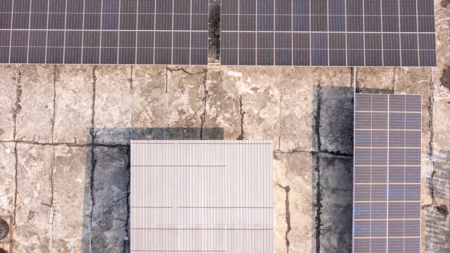 Aerial view of solar panels installed on a weathered concrete rooftop, Klaten, Central Java, Indonesia.