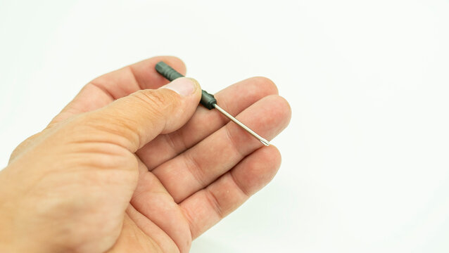 A hand holds a small Phillips screwdriver designed for precision work, isolated against a white background. The tool features a slender metal tip and a comfortable handle. The background is simple and
