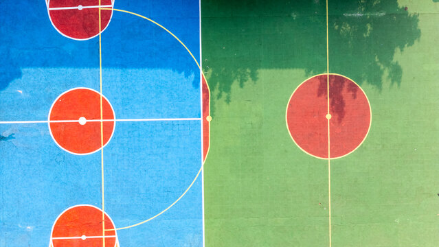 Aerial view of a colorful basketball court with blue and green painted surfaces and red circles in Klaten, Central Java, Indonesia.