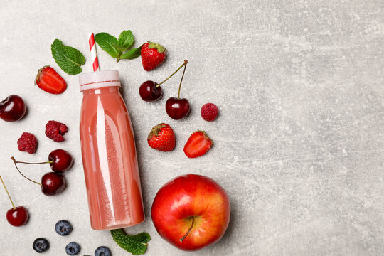 Tasty smoothie in bottle and fresh ingredients on light grey textured background, flat lay. Space for text