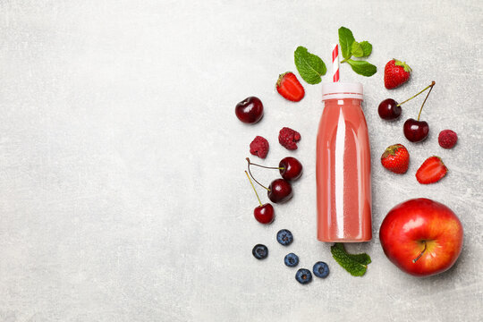 Delicious smoothie in bottle and fresh ingredients on light grey textured background, flat lay. Space for text