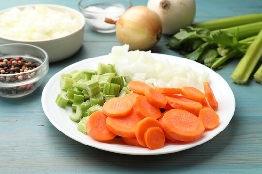 Fresh celery, carrots, onions and spices on light blue wooden table, closeup