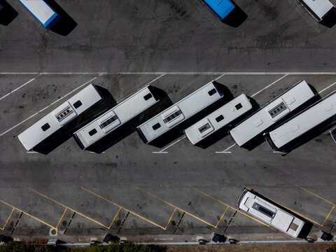 Aerial view of white buses parked in a diagonal formation in a paved lot in Evora, Evora District, Portugal.