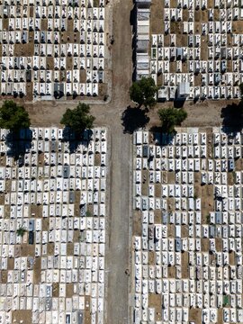 Aerial view of the cemetery with organized rows of white tombstones, gravel paths, and green trees in Evora, Evora District, Portugal.