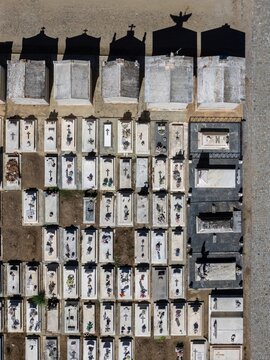 Aerial view of a cemetery with rows of white stone tombs, crosses, and long shadows cast by monuments in Evora, Evora District, Portugal.
