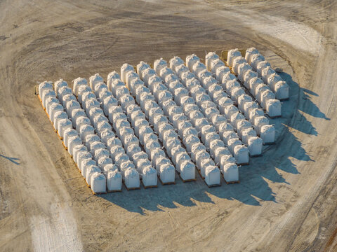 Aerial view of bulk bags filled with processed sea salt arranged in neat rows at an industrial storage yard in Aigues-Mortes, Occitanie, France.