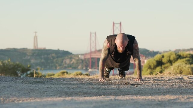Strong tattooed man doing push-ups outdoors in lisbon