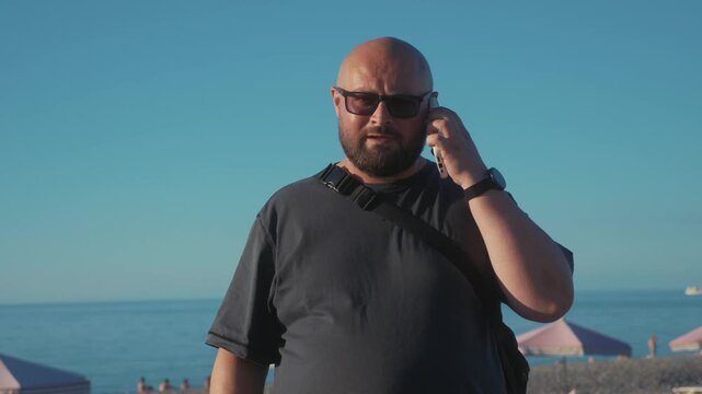 Tourist on beach vacation abroad facing roaming problems, raising smartphone to find mobile signal and restore connection after interrupted call.