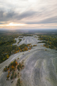 Aerial view of the rocky ridges and autumnal forests under a sunset sky in Tervola, Lapland, Finland.