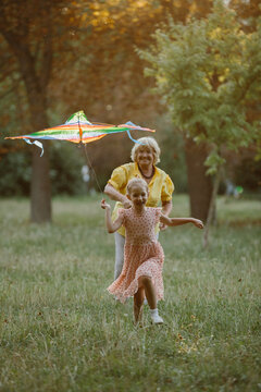 Grandmother and granddaughter flying kite enjoying park
